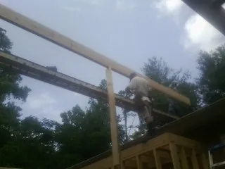 Carpenter setting a ridge beam over a new addition frame — Ice Dam Removal by Roofing Brothers in Campobello