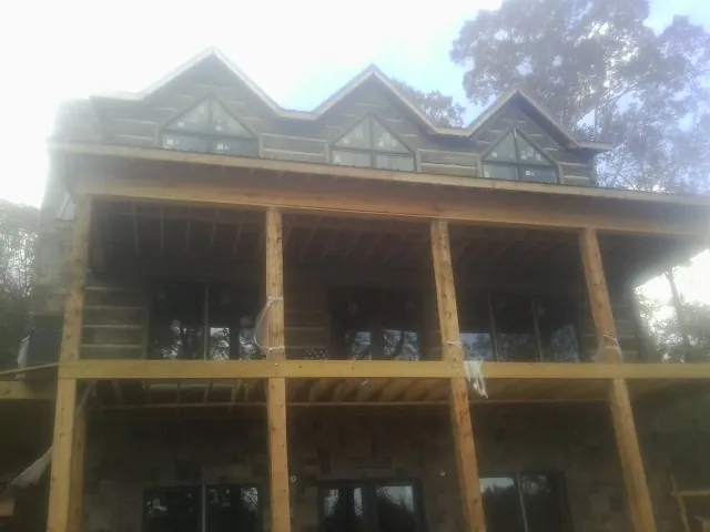 Dormers and porch framing on a large log home under construction — Roof Coating work by our crew in Campobello