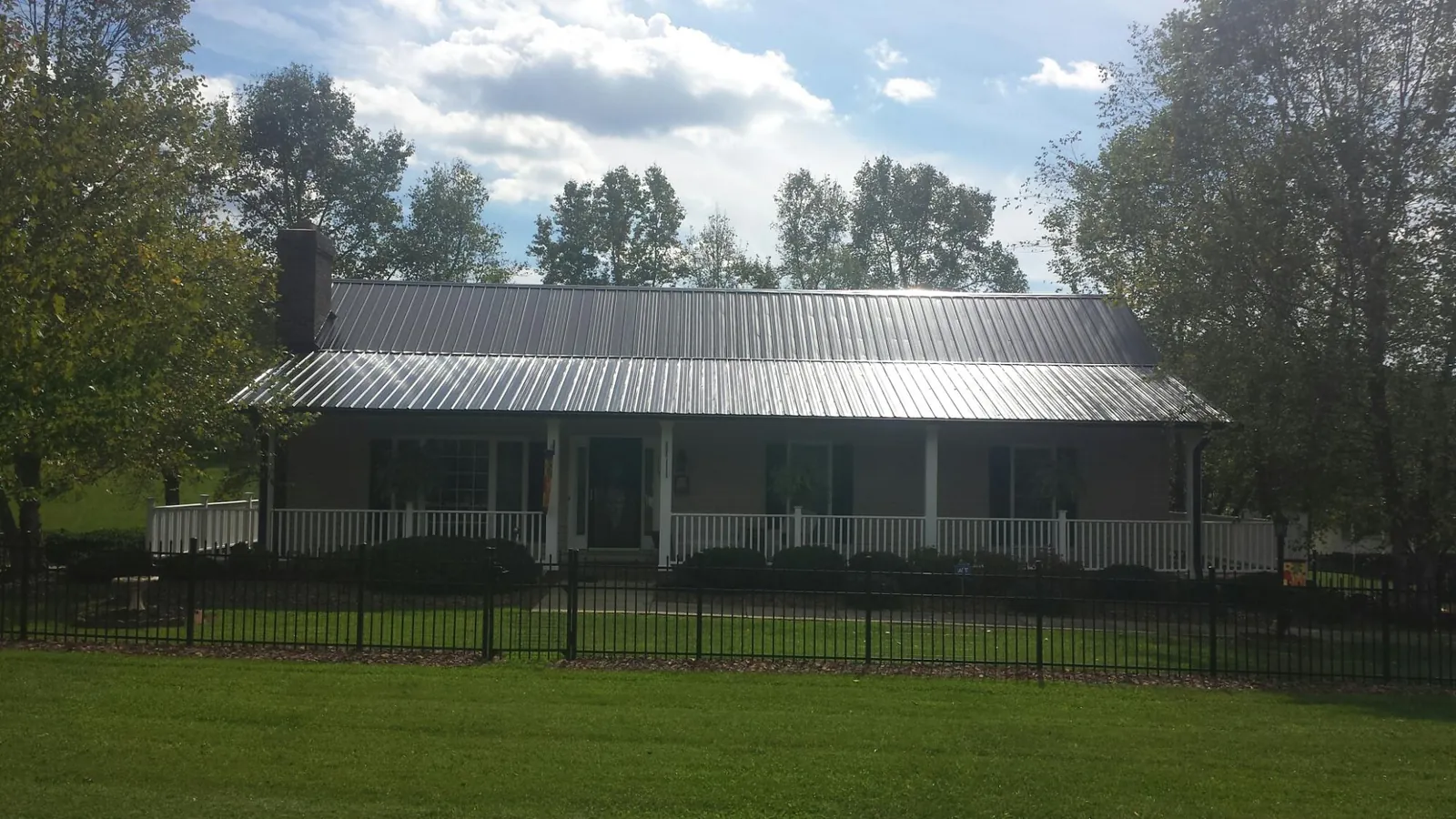 Gray metal roof on a brick ranch with a full width front porch — Gutter Guard Installation work by our crew in Campobello