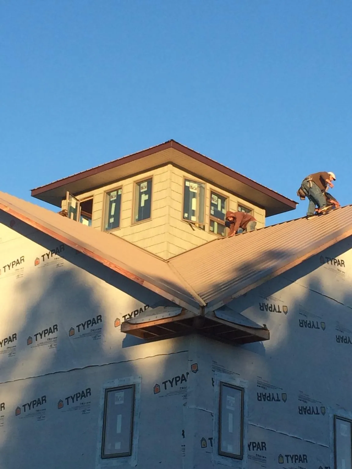 Roofers working around a rooftop cupola on a new metal roof at sunset — Roof Waterproofing in Campobello by Roofing Brothers